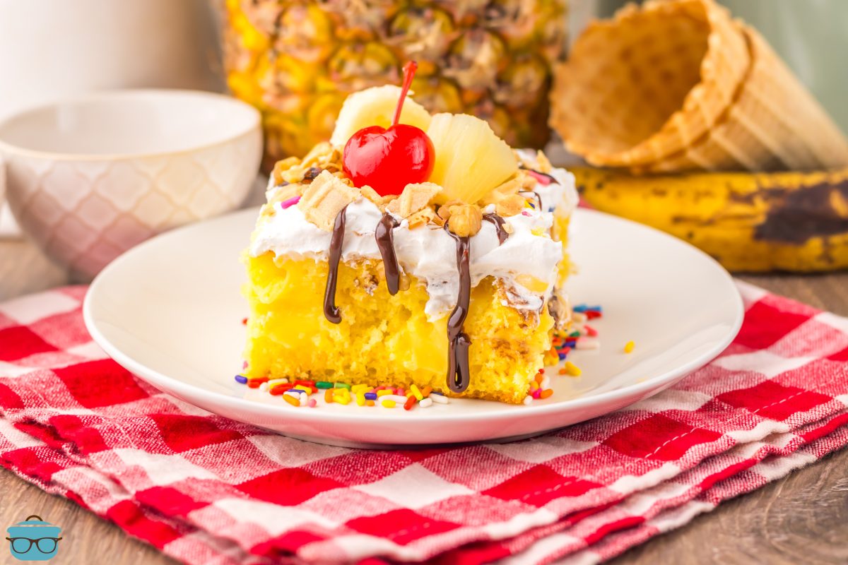 A white plate with a slice of Banana Split Poke Cake. 