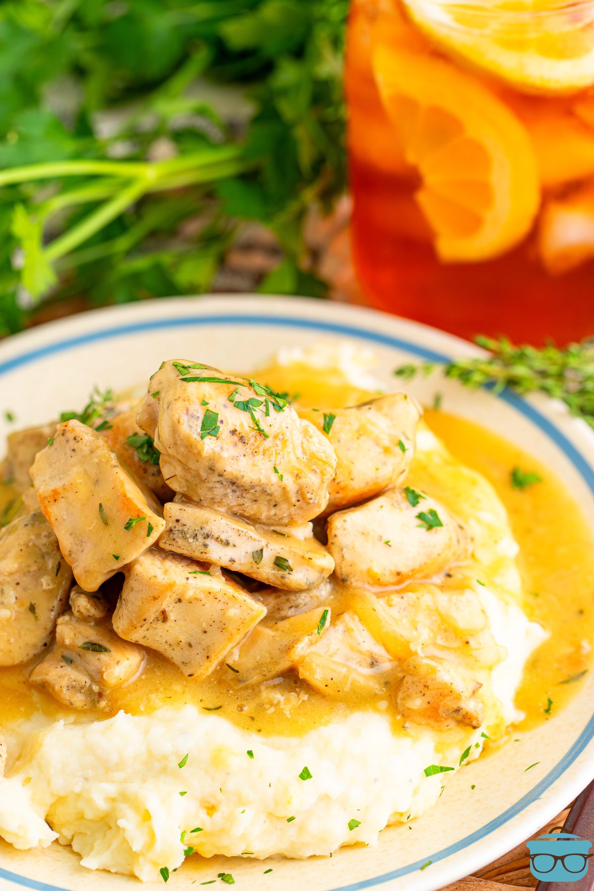 A plate of Chicken Bites in Gravy with a glass of tea.