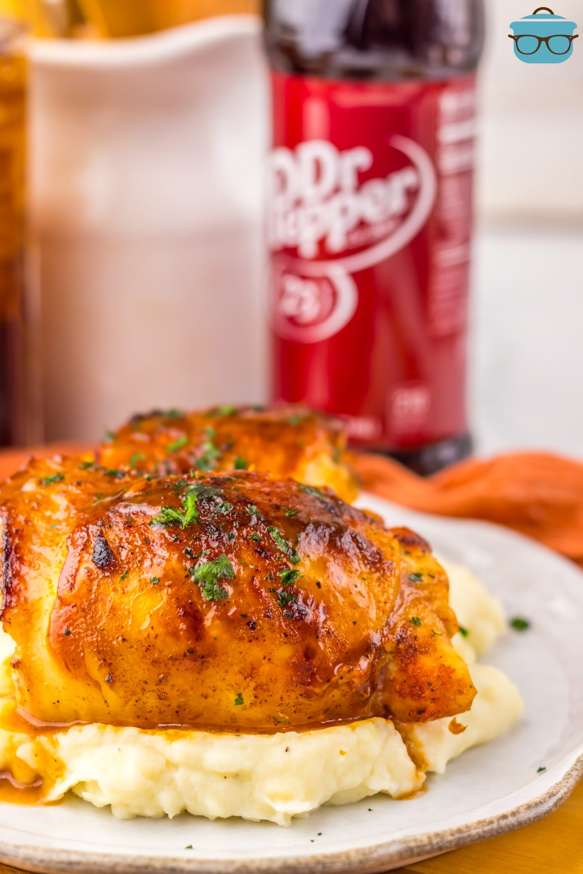 A plate of Crock Pot Dr Pepper Chicken Thighs on top of a bed of mashed potatoes. 