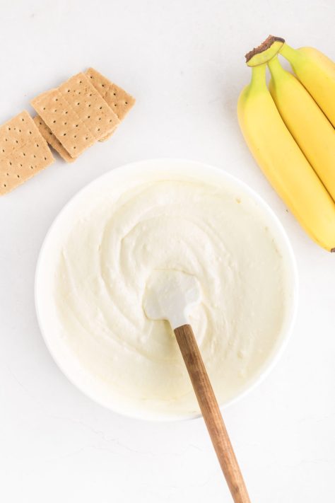 A bowl of pudding mix, whipped topping, and milk being mixed together.