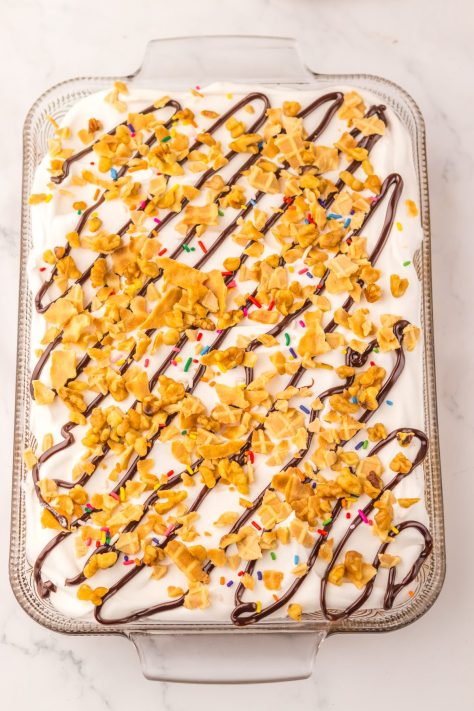 Crushed cone pieces and fudge over the top of a cake.