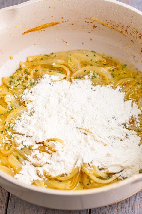 Flour being added to sauteed onions.