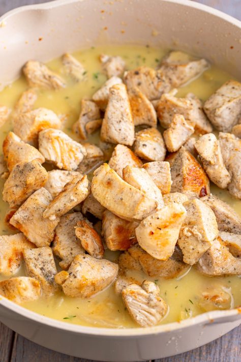 Chicken in a gravy in a skillet.