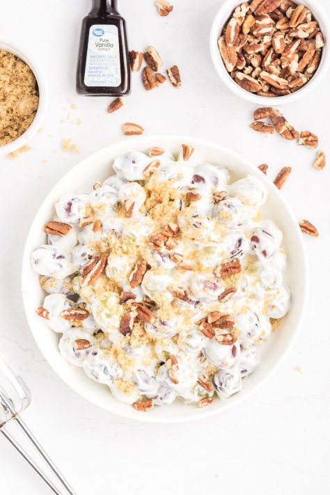 A bowl of Grape Salad with chopped nuts and brown sugar.