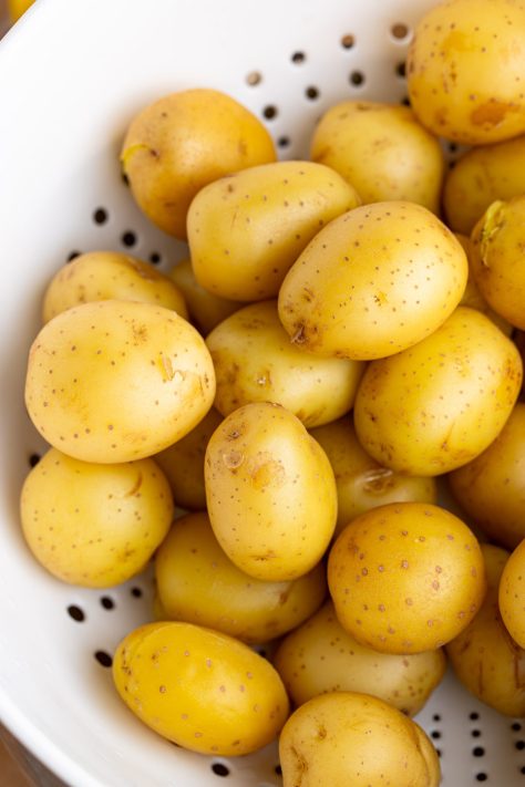 Cooked potatoes cooling in a strainer.