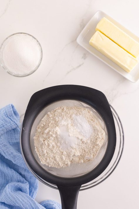 Flour and dry baking ingredients being sifted into a bowl.