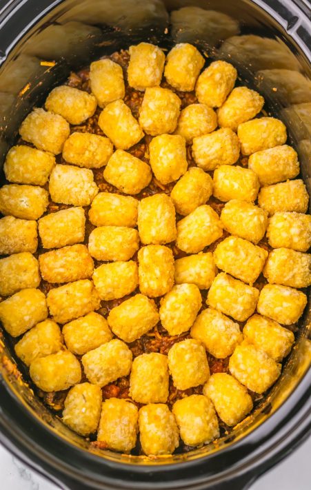 Tater tots on top of salt, pepper, chili seasoning, garlic, diced tomatoes with green chilies, tomato sauce and half cup of cheese in a Slow Cooker.