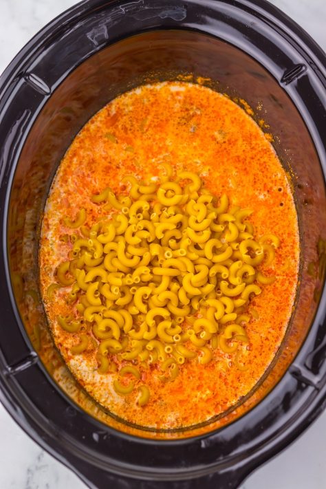 Macaroni being added to a beefy sauce mixture in a Slow Cooker.