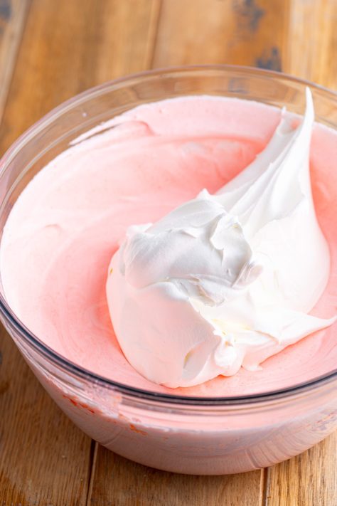 Whipped topping being added to s pudding jello mixture.