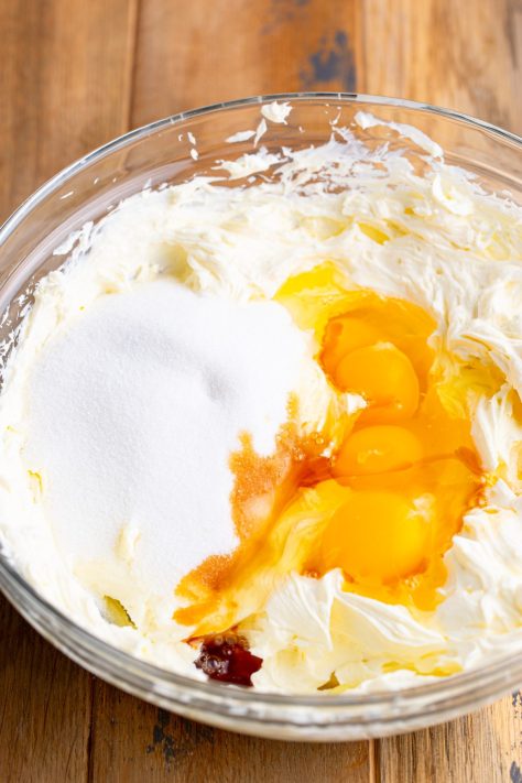 Eggs, sugar, vanilla, and cream cheese being mixed together.