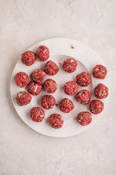 Raw, homemade meatballs on a plate.