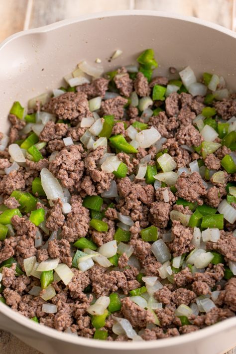 Ground beef, onion, and diced peppers in a pot being cooked.