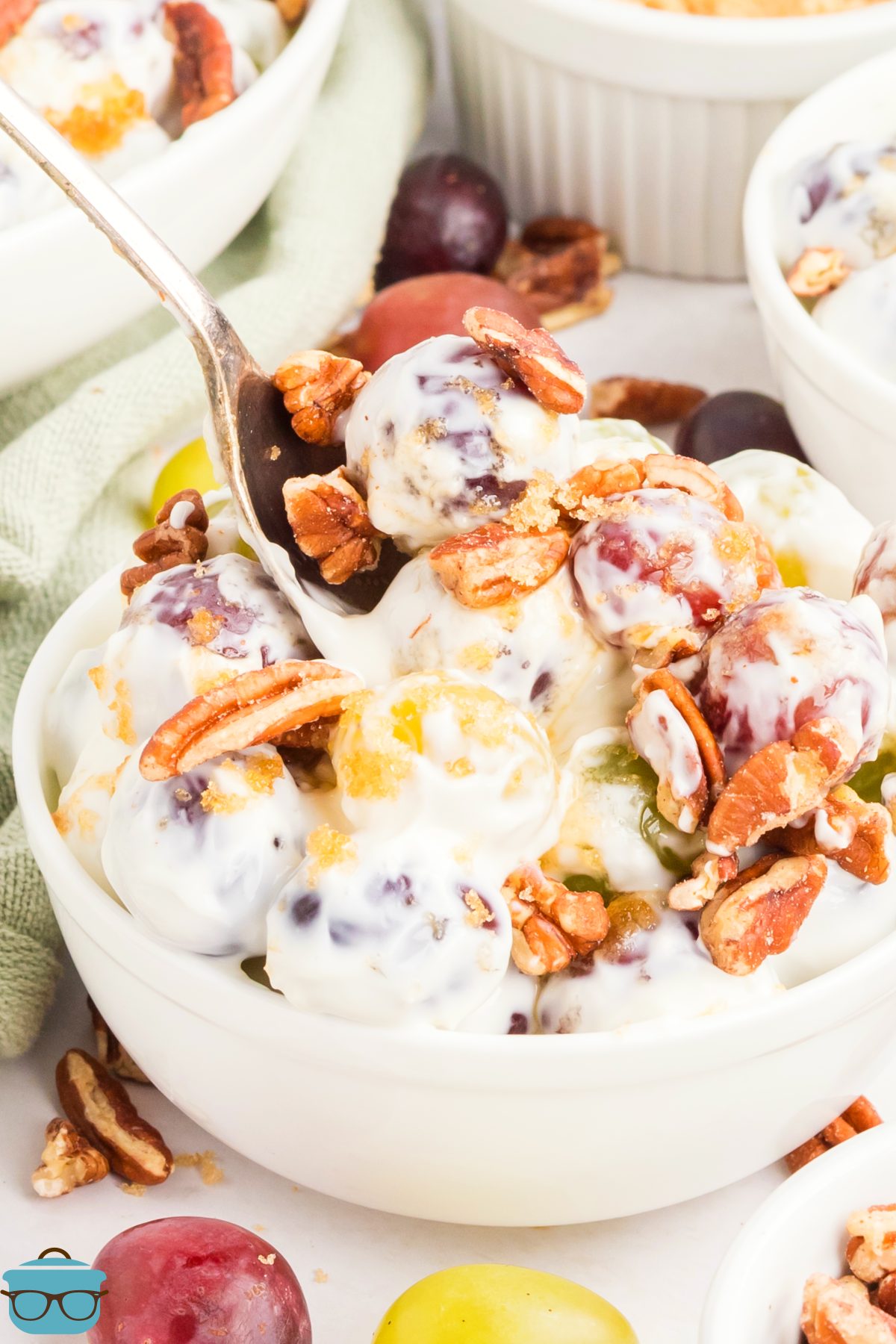A spoon getting a scoop of Grape Salad from the bowl.