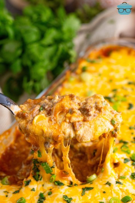 A serving utensil getting a serving of Ground Beef Texas Trash from the glass baking dish.