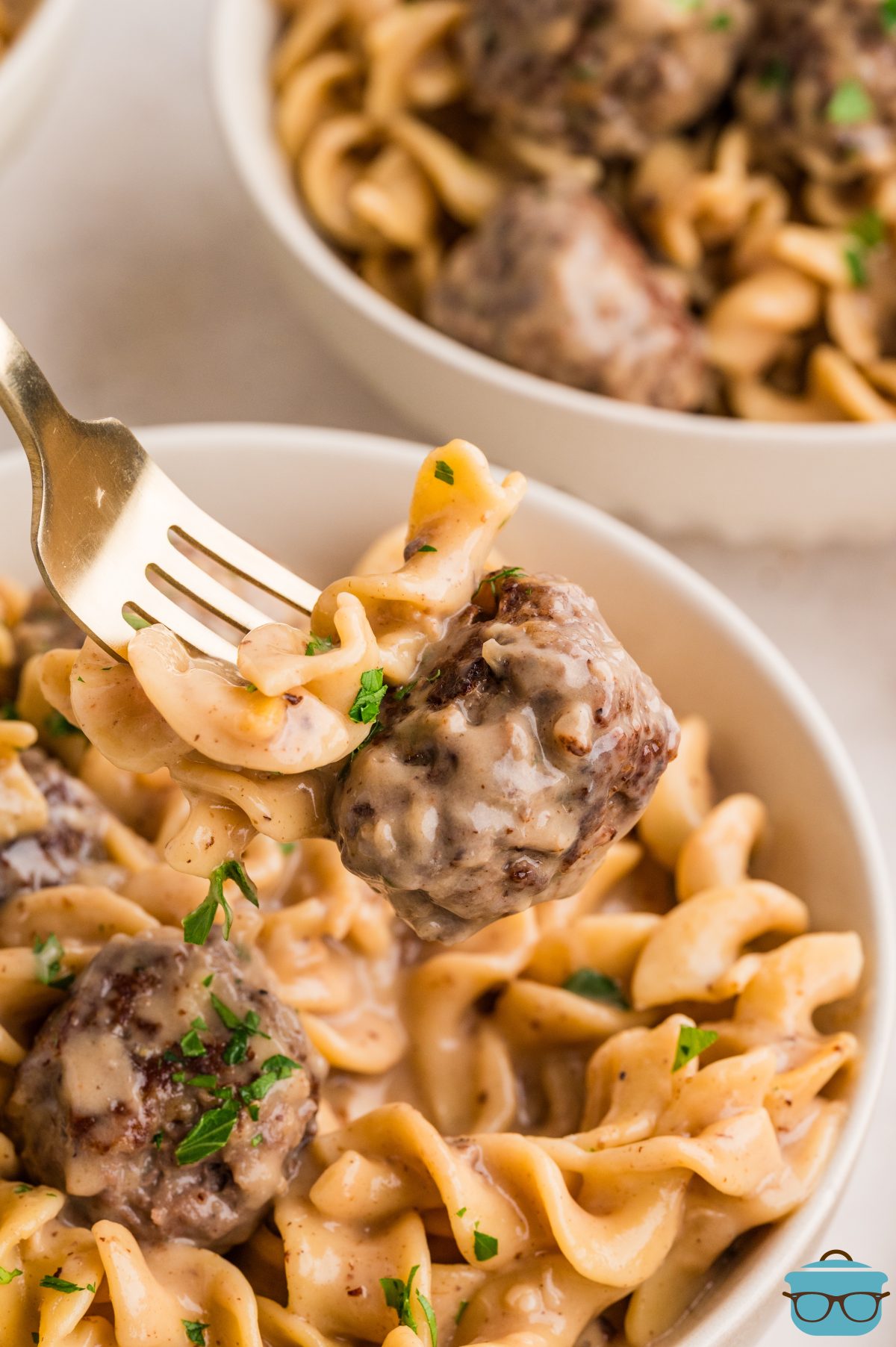 A fork getting a bite of Swedish Meatballs with Noodles from the bowl.