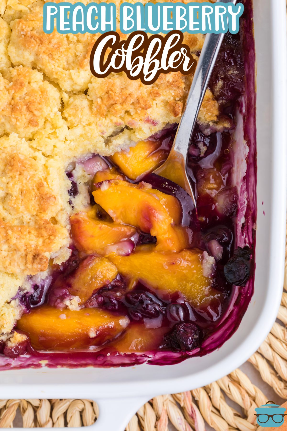 A spoon getting a scoop of the Peach Blueberry Cobbler from the baking dish.