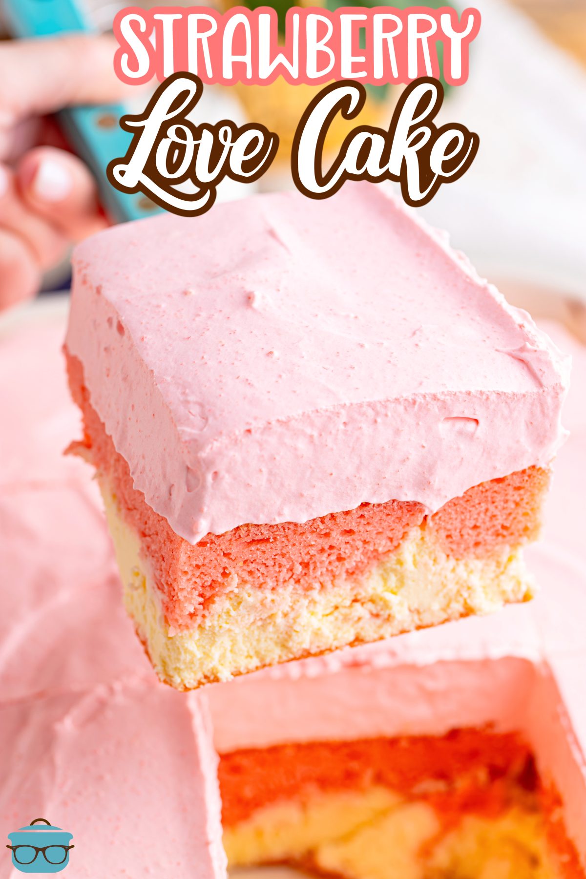 A slice of Strawberry Love Cake above the rest of the cake.