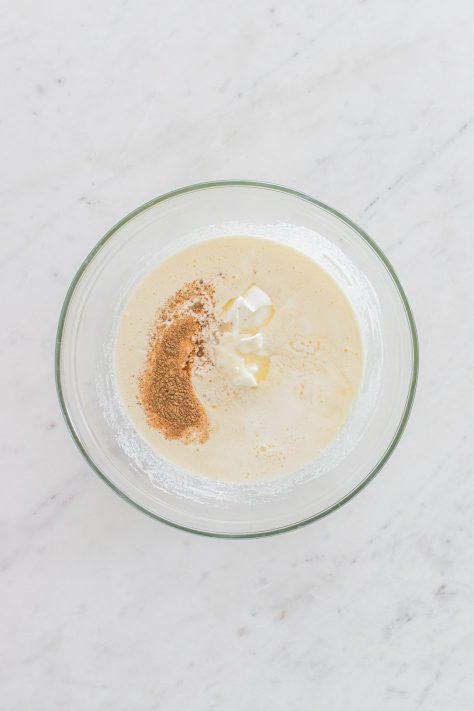 A bowl of sugar, eggs, sour cream, milk, melted butter, vanilla extract, butter extract, nutmeg, and salt.