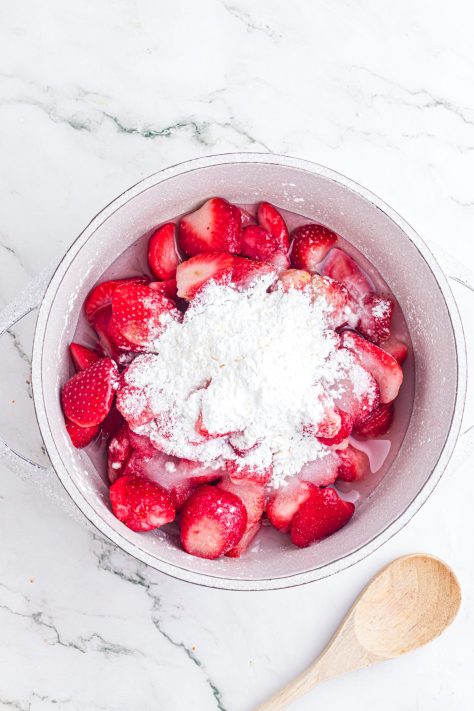 Strawberries and sugar in a saucepan.