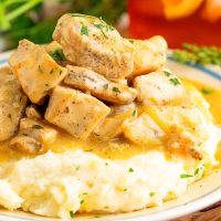 A dinner plate of mashed potatoes and Chicken Bites with gravy.