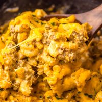 A wooden serving utensil stirring a scoop of Crock Pot Cheeseburger Helper.