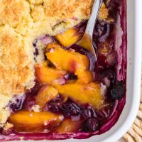 Looking down on the corner of Peach Blueberry Cobbler in a baking dish.