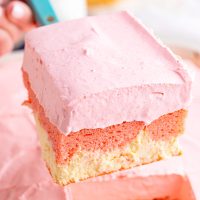 A slice of Strawberry Love Cake being held above the rest of the cake.