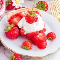 A plate of Strawberry Pie with a few frozen strawberries around the slice on a dessert plate.