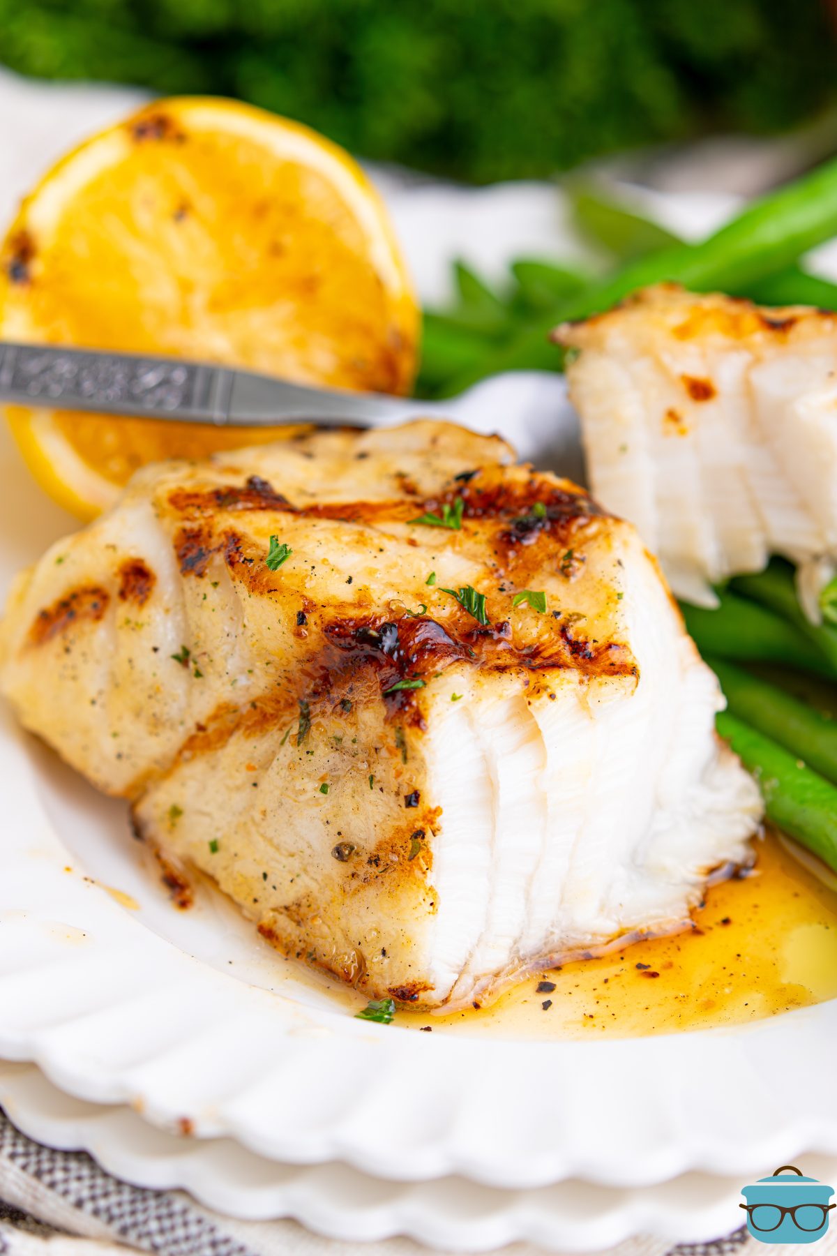A piece of Grilled Sea Bass with a bite on a fork next to it.