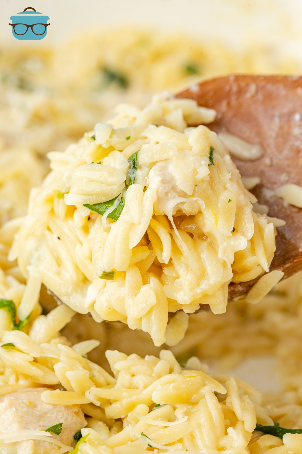 A serving utensil getting a scoop of Lemon Chicken Orzo from the dish.