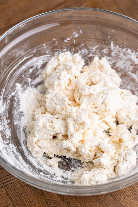 A bowl of sour cream and self rising dough being mixed to create a dough.