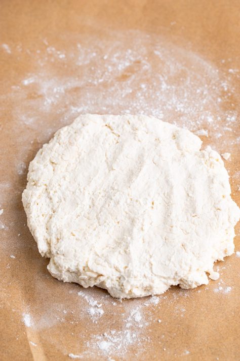A circle of dough on a floured surface.