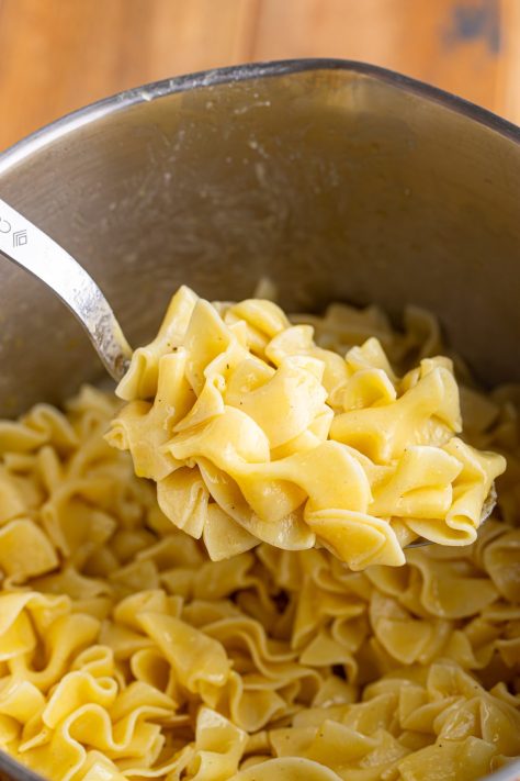 Buttered Noodles on a spoon over the pot of noodles.