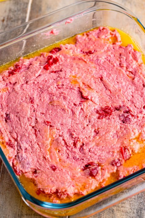 A baking dish with melted butter and cherry pie biscuit dough.