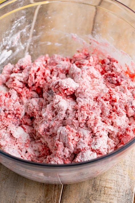 Cherry pie filling and dry ingredients for biscuits being mixed together.