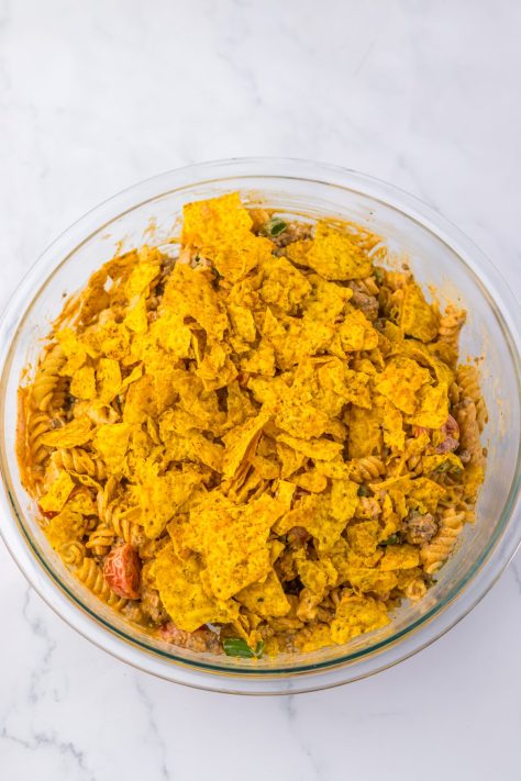 Crushed Cool Ranch Doritos being added to a Pasta Salad.