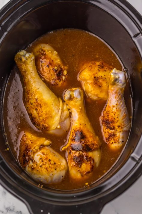 Seared drumsticks in a Crock Pot with the sauce.