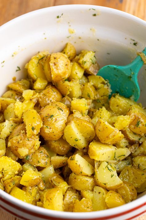 Cut up potatoes with olive oil, lemon juice, dill, sugar, garlic, oregano, salt, and pepper.