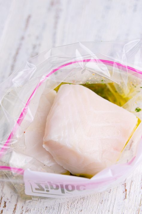 Sea bass being coated in marinade.