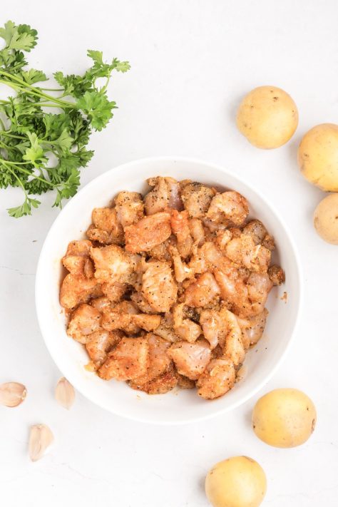 Raw chicken and seasonings in a bowl.