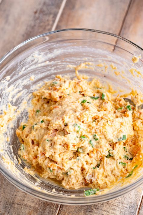 Shrimp and green onions being added to a batter in a bowl.