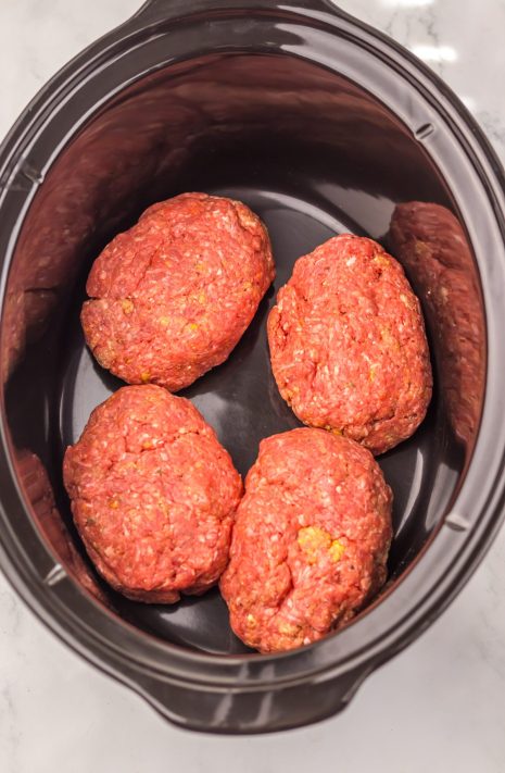 Four raw Salisbury Steak patties in a Slow Cooker.