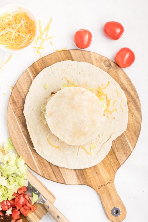 Smaller cut our tortilla being placed over a crunchwrap.