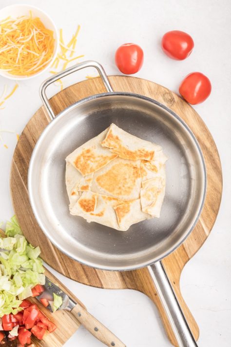A Taco Bell copycat Crunchwrap being toasted in a skillet.