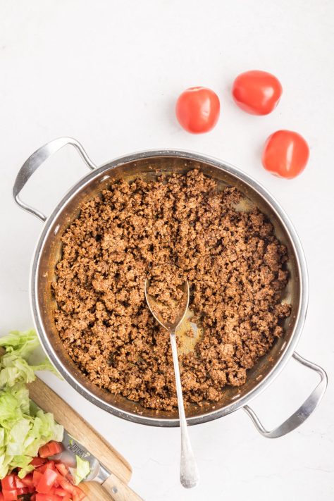 Taco seasoned ground beef cooking in a skillet.