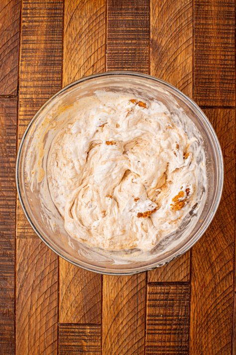 A bowl of Biscoff cookie butter, vanilla extract, and crushed Biscoff cookies.