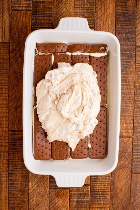 Half the Biscoff cookie mixture being spread over ice cream sandwiches.