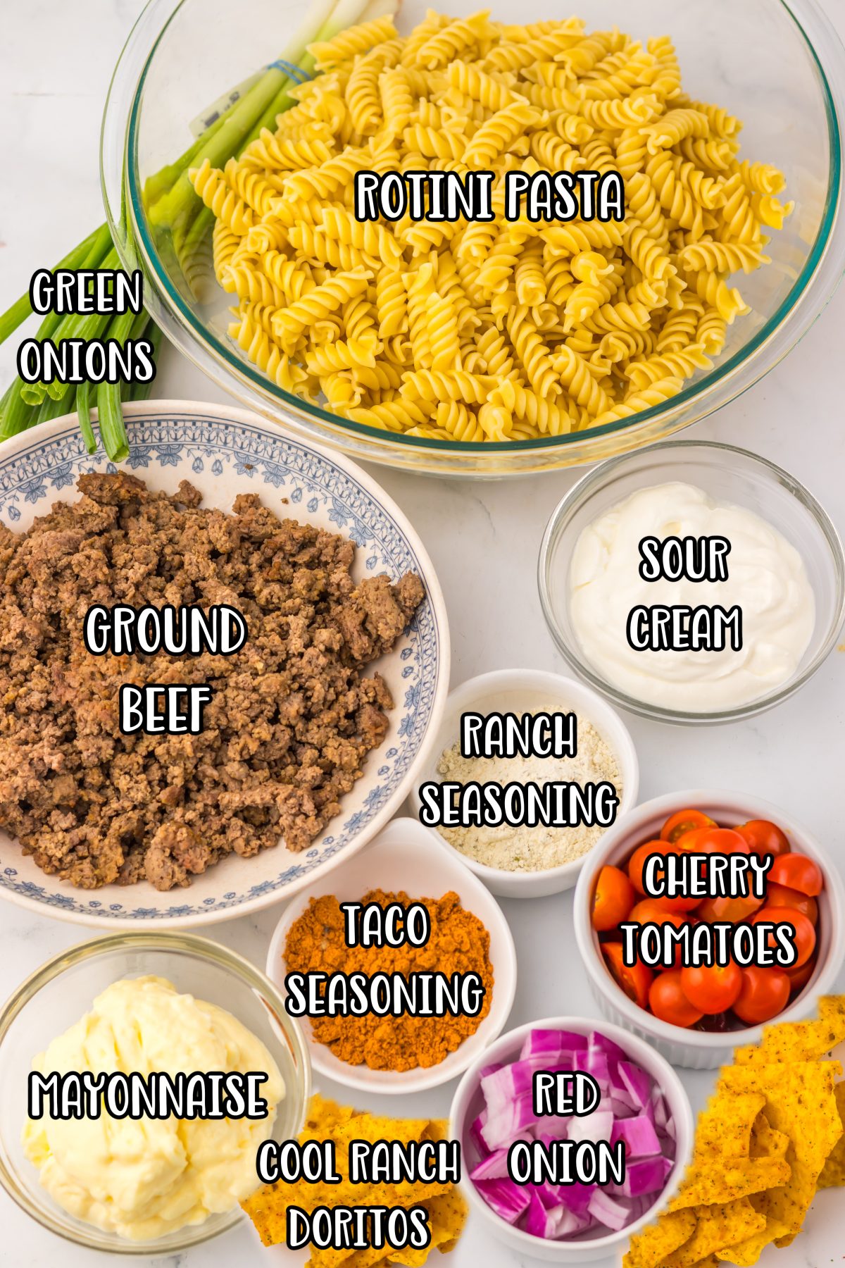 Rotini pasta, ground beef, taco seasoning, mayonnaise, sour cream, ranch seasoning mix, red onion, cherry tomatoes, cheddar cheese, Cool Ranch Doritos, and green onions.