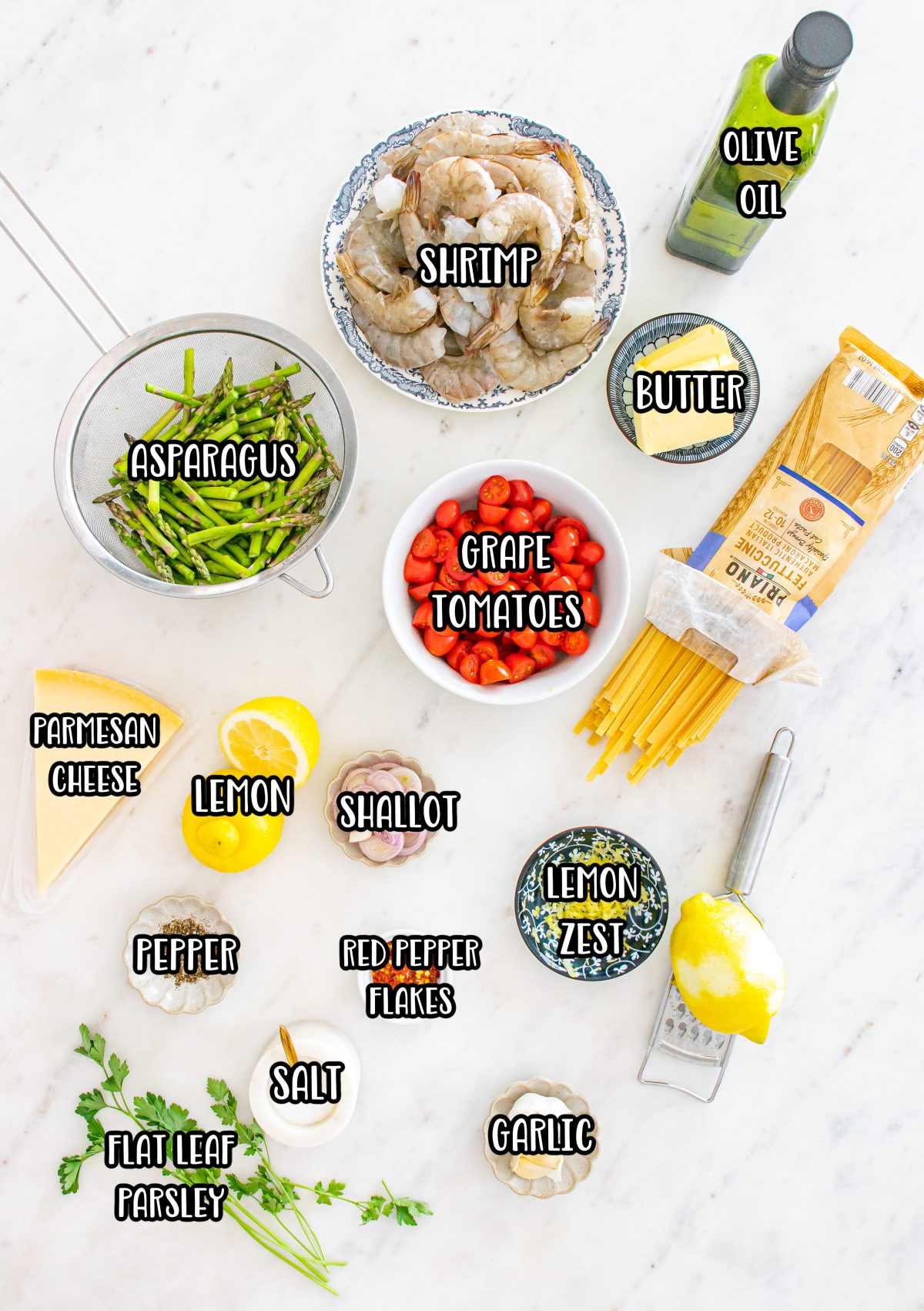 Asparagus, cherry tomatoes, garlic, shallot, olive oil, salt, black pepper, shrimp, red pepper flakes, butter, lemon zest, lemon juice, parsley, Parmesan cheese, lemon slices, and pasta.