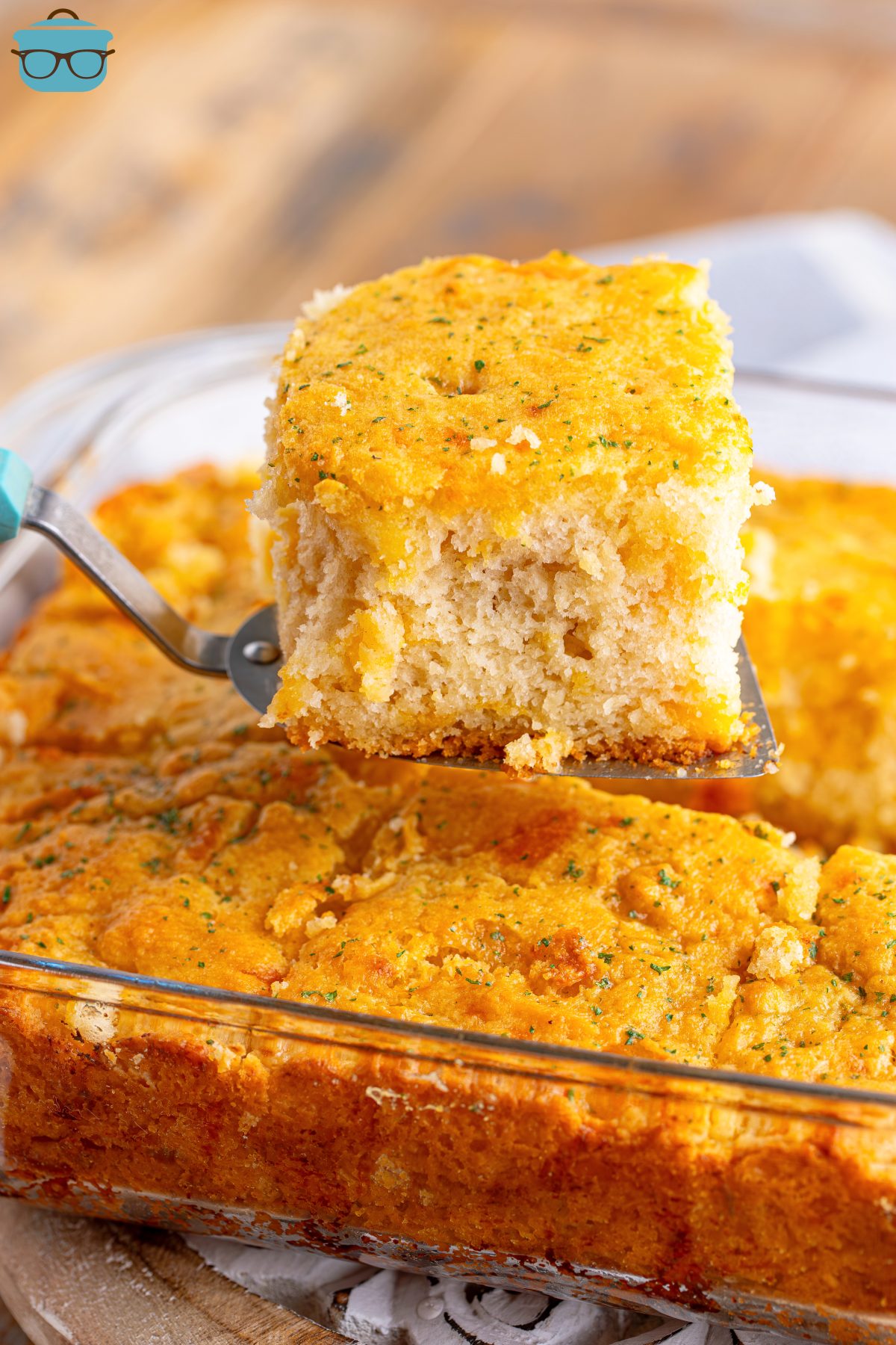 A serving utensil lifting one of the freshly baked Cheddar Bay Butter Swim Biscuits from the glass dish.